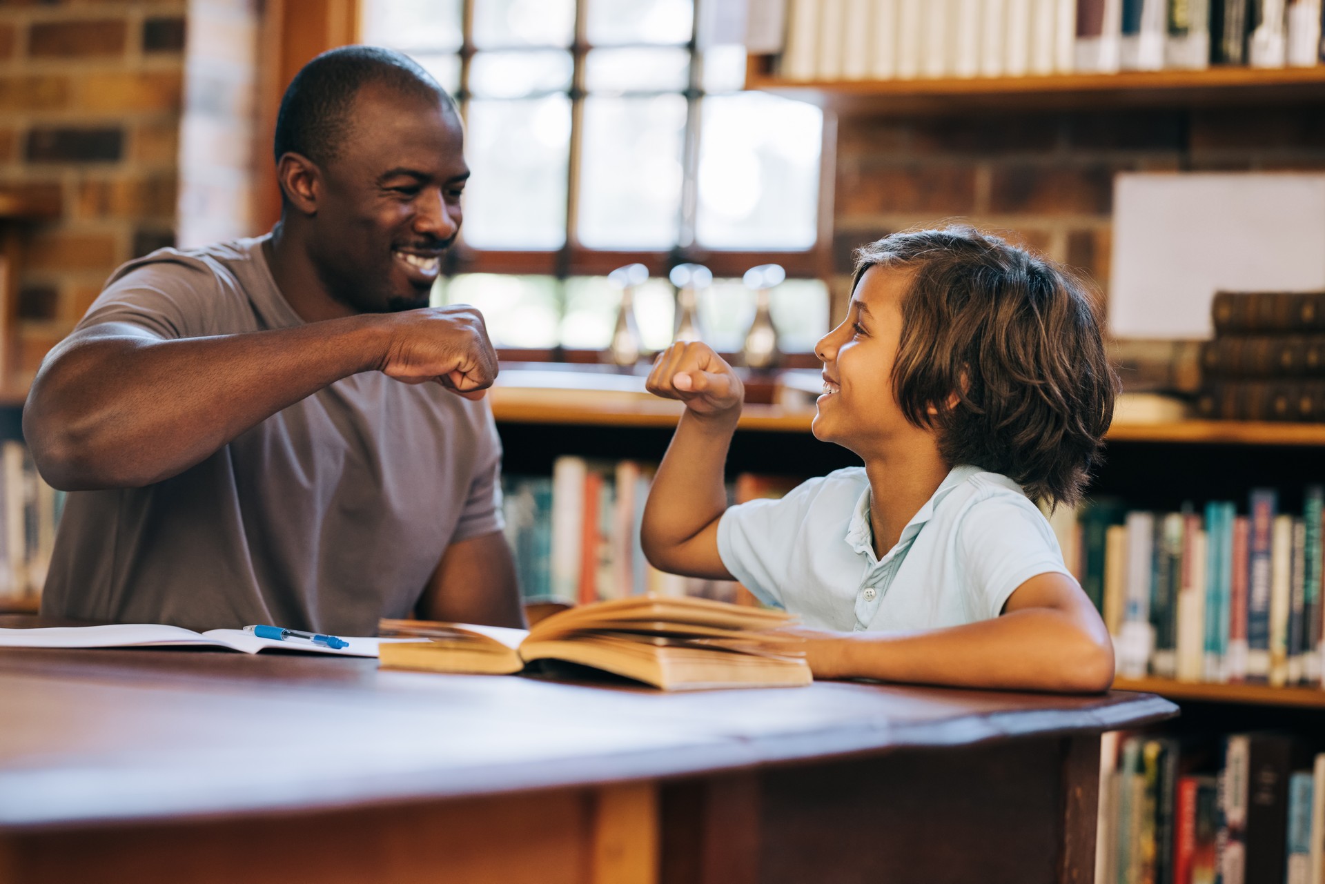 Teacher and student giving each other a high five in a library