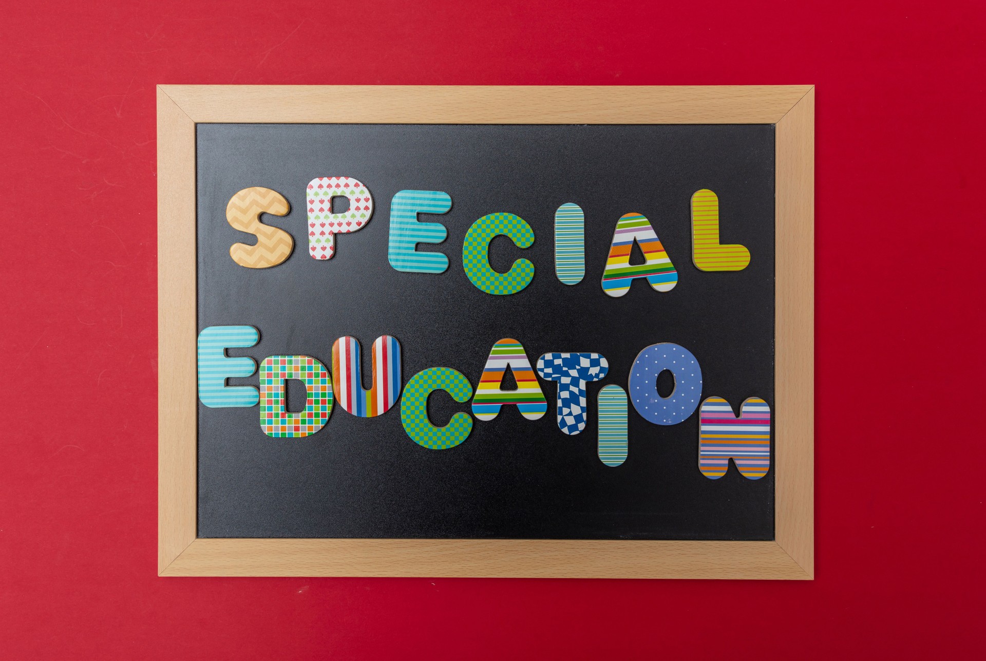 Black chalkboard with wooden frame, text special education in colorful letters, red wall background